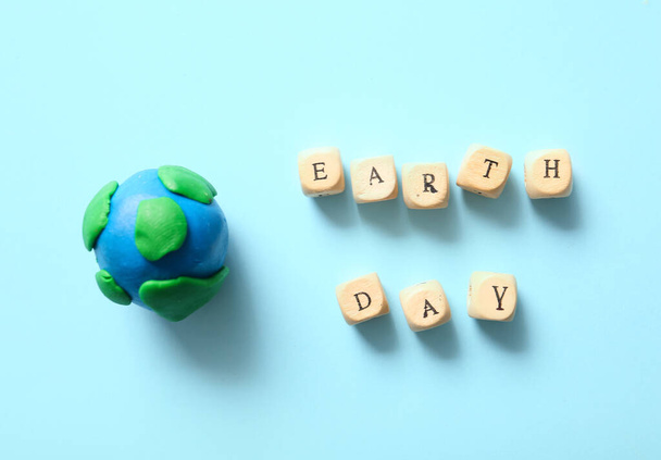 Model van aarde en houten kubussen met tekst AARDE DAG op kleur achtergrond. Feestdag op aarde. - Foto, afbeelding
