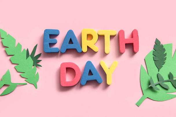 Text EARTH DAY and paper leaves on pink background, closeup. - Photo, Image
