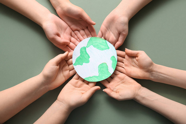 Hands holding paper planet Earth on green background. Earth Day celebration. - Photo, Image