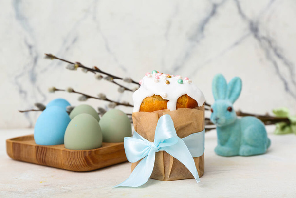 Sabroso pastel de Pascua con huevos, ramas de sauce y conejito de juguete sobre fondo blanco - Foto, imagen