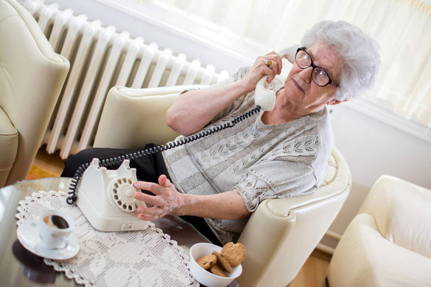 Femme âgée parlant au téléphone à la maison. - Photo, image
