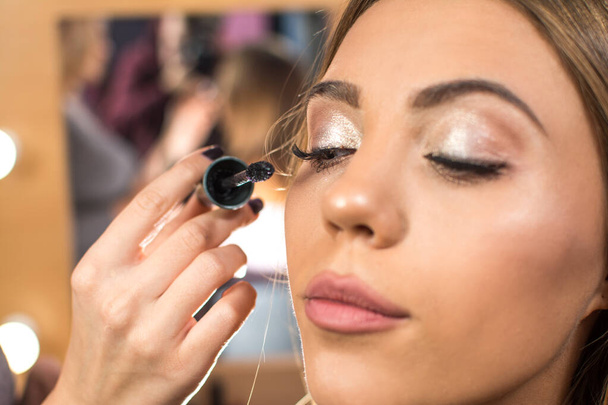 Make-up kunstenaar het toepassen van mascara op mode model. - Foto, afbeelding