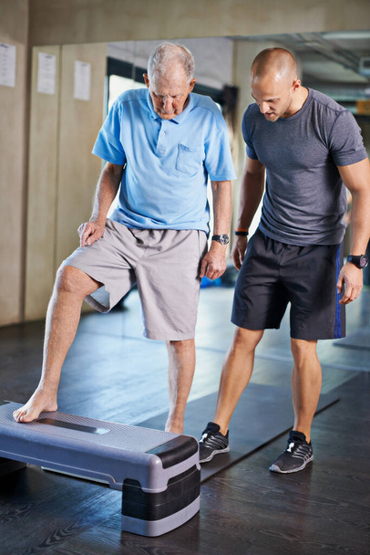 Fizioterapeuta, segítő és időskorú férfi kardio, képzés és idősgondozási támogatás. Férfiak, tornaterem és testmozgás az egészség, wellness és coaching aerob lépés az érett rehab és jólét. - Fotó, kép