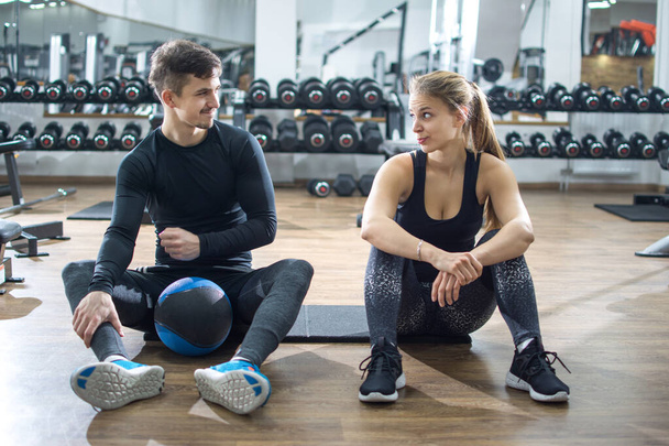 Αθλητικό ζευγάρι που μιλάει κατά τη διάρκεια του διαλείμματος άσκησης στο γυμναστήριο - Φωτογραφία, εικόνα