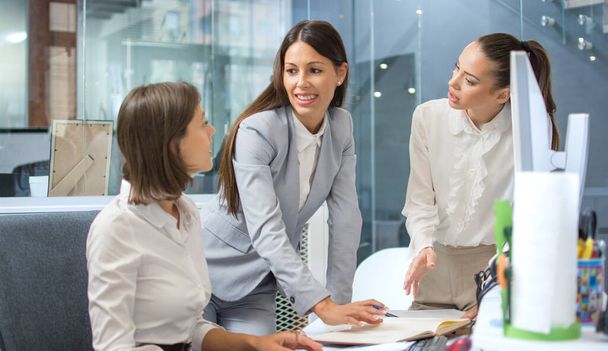 Young business woman with ironic smile explaining mistakes to her female employees and arguing about company issue. - Photo, Image