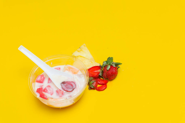 es buah ou sup buah est un cocktail de fruits indonésien désert de glace, contient de la fraise, de l'ananas et d'autres fruits tropicaux mélangés avec du glaçon et du lait condensé. isolé sur fond jaune. - Photo, image