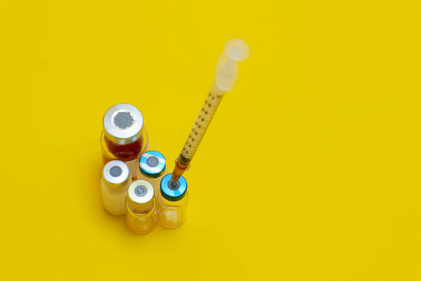 foto di diversi flaconcini di medicinale per iniezione e siringhe isolate su fondo giallo - Foto, immagini