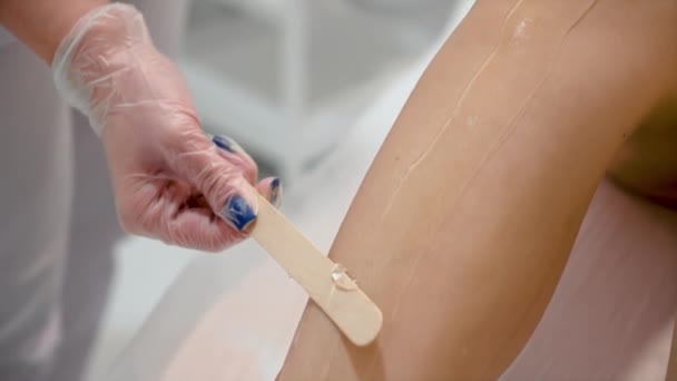 La mano del cosmetólogo en los guantes protectores aplica el gel transparente a la pierna femenina de cerca. Mujer cliente preparándose para el procedimiento de depilación. Cuidado del cuerpo femenino, piel lisa después de la depilación, medicina - Imágenes, Vídeo