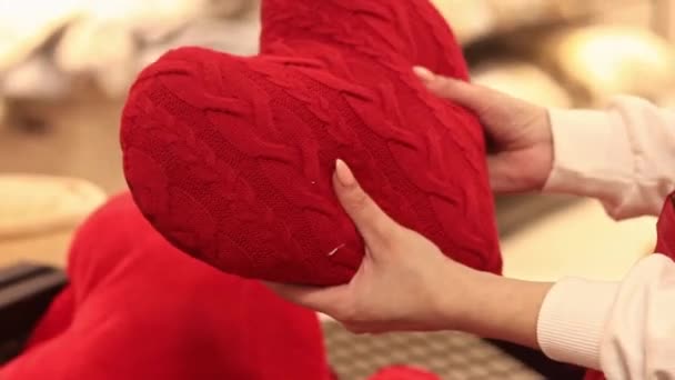 Kiev, Ucraina - 26 marzo 2024: Le mani delle donne tengono un cuscino a forma di cuore, primo piano. Vendere giocattoli in un negozio. Primo piano di un acquirente che sceglie un peluche. San Valentino - Filmati, video
