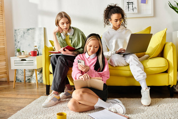 Három különböző tinédzser lány, akik azzal vannak elfoglalva, hogy együtt tanuljanak a kanapén, miközben egy könyvet néznek.. - Fotó, kép