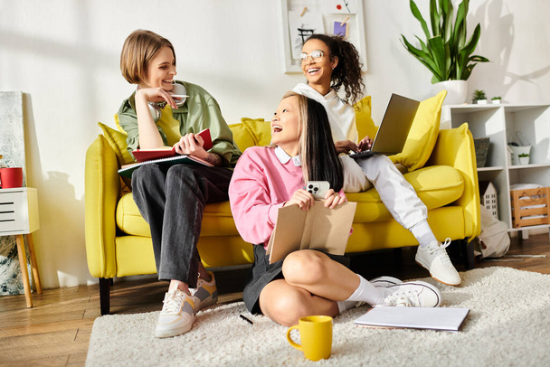 Různorodá skupina dospívajících dívek se shromáždí na pulzujícím žlutém gauči, aby studovaly, smály se a vzájemně se podporovaly v teplém a útulném prostředí. - Fotografie, Obrázek