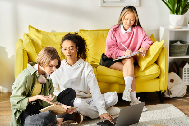 Grupa wielorasowych nastolatek siedzących na podłodze, pochłoniętych wspólną nauką na laptopie w domu. - Zdjęcie, obraz
