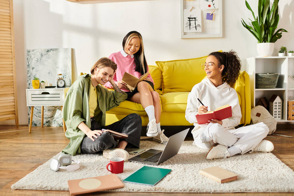 A group of teenage girls of different ethnicities sitting together on a yellow couch, studying and enjoying each other company. - Фото, изображение