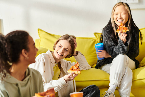 Zróżnicowana grupa nastolatek siedzi razem na żywej, żółtej kanapie, symbolizując przyjaźń i wspólnotę. - Zdjęcie, obraz