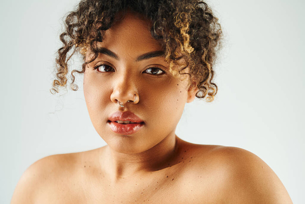 Красива афроамериканська жінка з кучерявим волоссям вражає позу на яскравому тлі. - Фото, зображення