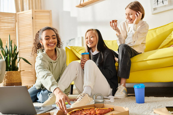 Diverse tienermeisjes bonding over pizza terwijl gezeten op de vloer in een gezellige omgeving. - Foto, afbeelding