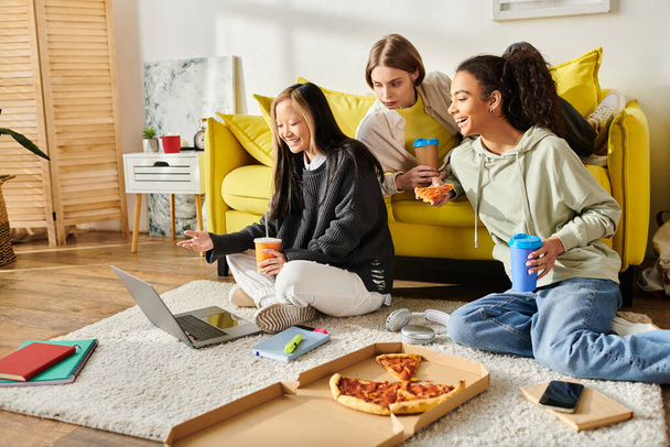 Διαφυλετικές έφηβες που απολαμβάνουν την πίτσα μαζί, κάθονται στο πάτωμα και μοιράζονται ένα γεύμα σε ένα ζεστό, σπιτικό περιβάλλον. - Φωτογραφία, εικόνα