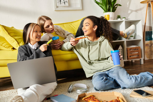 Zróżnicowana grupa nastolatek delektujących się pizzą siedząc na podłodze, łącząc się jedzeniem i przyjaźnią. - Zdjęcie, obraz