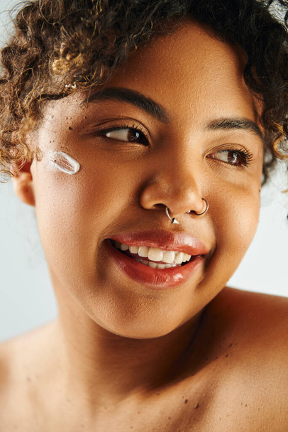 Μια όμορφη Αφρο-Αμερικανίδα ποζάρει, δείχνοντας το σκουλαρίκι της στη μύτη.. - Φωτογραφία, εικόνα