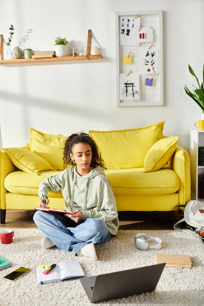 Ein Teenager-Mädchen tief im E-Learning, auf dem Boden vor einer gelben Couch sitzend. - Foto, Bild