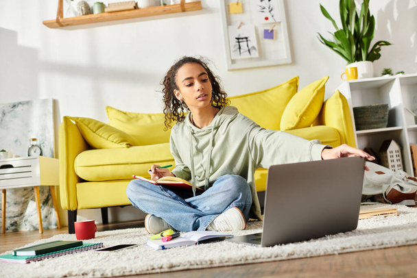Een tienermeisje dat thuis studeert, diep verdiept in e-learning op haar laptop terwijl ze op de vloer zit. - Foto, afbeelding