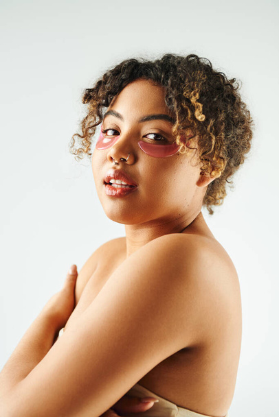 Gros plan d'une femme afro-américaine arborant avec confiance un soutien-gorge élégant sur fond vibrant. - Photo, image