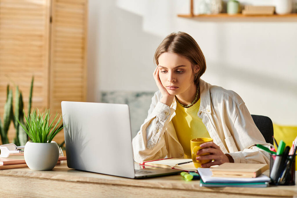 Une adolescente concentrée étudiant dans un bureau en bois avec un ordinateur portable ouvert devant elle pour l'apprentissage en ligne. - Photo, image