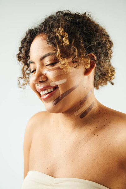 Приваблива афроамериканська жінка з основою на обличчі позує на яскравому тлі. - Фото, зображення