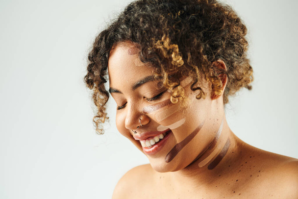 Atrakcyjna Afroamerykanka z fundamentem na twarzy pozuje na tętniącym życiem tle. - Zdjęcie, obraz
