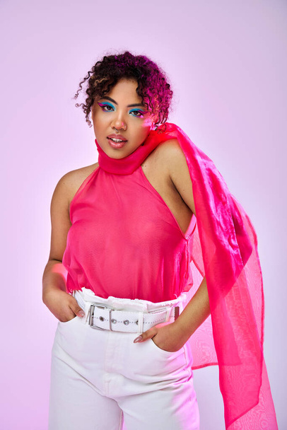 Афроамериканка изящно позирует в розовом топе и белых брюках на ярком фоне. - Фото, изображение