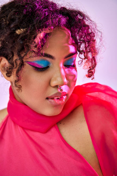 Uma bela mulher afro-americana posa ativamente em um vestido rosa com maquiagem brilhante. - Foto, Imagem