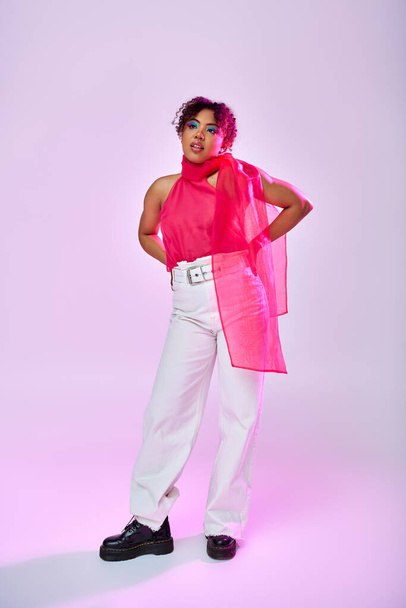 Африканська американка позує витончено в рожевій сорочці і білих штанях. - Фото, зображення