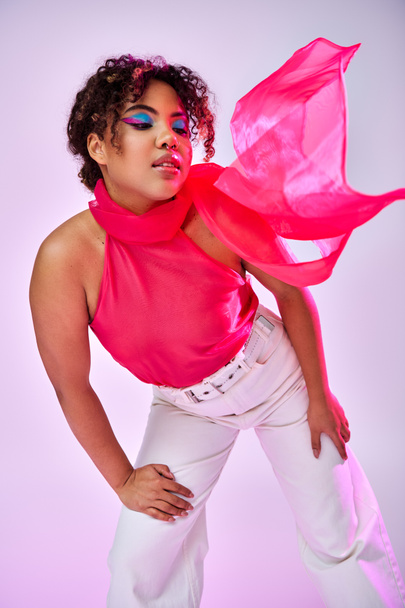 Een stijlvolle Afro-Amerikaanse vrouw die actief poseert in een witte broek en een roze top. - Foto, afbeelding