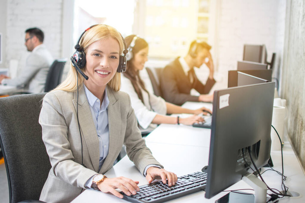 Young blonde female receptionist with headset in office - Photo, Image