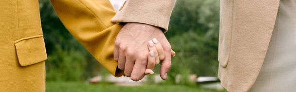 Крупним планом дві людини тримають руки, пальці переплітаються в красивому зеленому парку. - Фото, зображення
