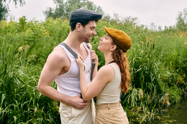 Mężczyzna i kobieta, piękna para, stojący razem w bujnym zielonym parku, cieszący się romantyczną randką w naturalnym otoczeniu. - Zdjęcie, obraz