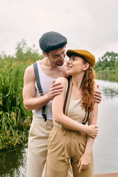 Een man en vrouw genieten van een romantische avond samen bij een rustig meer in een groen park. - Foto, afbeelding