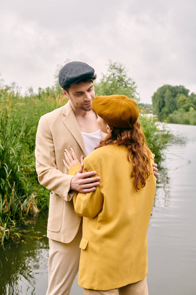 Een man en vrouw genieten van een romantisch moment aan het water in een weelderige groene parkomgeving. - Foto, afbeelding