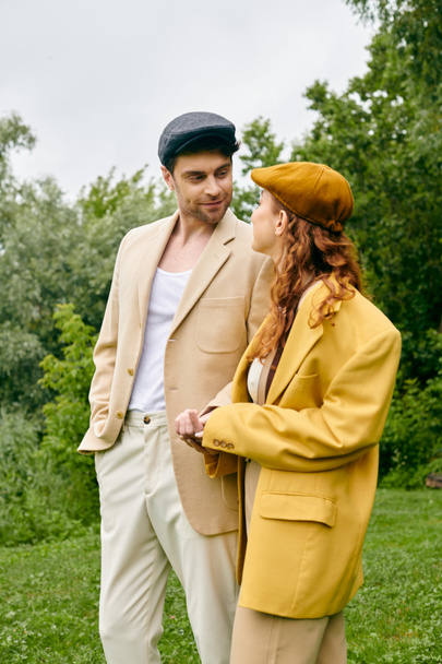 Mężczyzna i kobieta stojący blisko siebie w zielonym parku, emanujący poczuciem spokoju i romantyzmu. - Zdjęcie, obraz