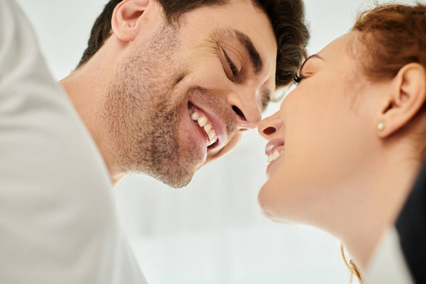 Muž láskyplně líbá ženskou tvář, když se radostně usmívá, ukazuje okamžik hluboké náklonnosti a štěstí. - Fotografie, Obrázek