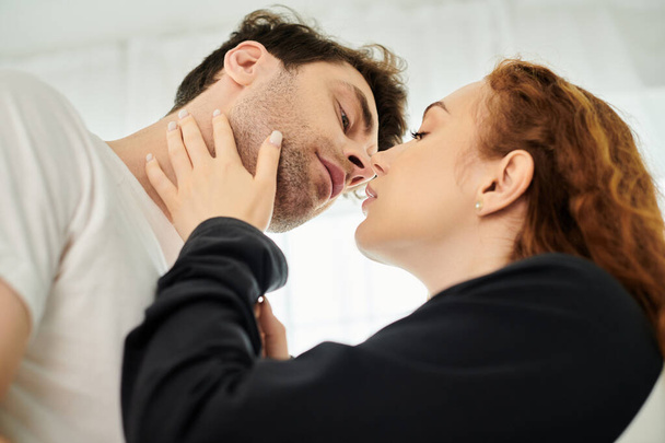 Mies ja nainen jakavat hellän suudelman, ilmaisevat läheisyyttä ja rakkautta makuuhuoneessa. - Valokuva, kuva