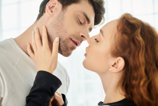 Een man en een vrouw delen een liefdevolle kus in een intiem moment. - Foto, afbeelding