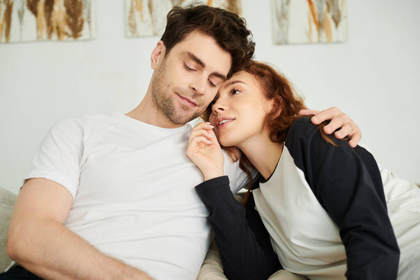 Um homem e uma mulher descansando confortavelmente em um sofá, curtindo a companhia uns dos outros em um ambiente acolhedor. - Foto, Imagem