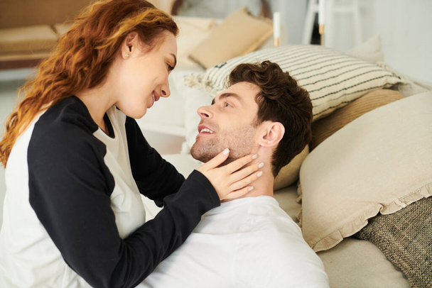 Un uomo e una donna riposano pacificamente su un letto, avvolti tra le braccia, godendo di momenti intimi insieme.. - Foto, immagini
