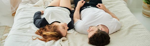 Mies ja nainen makaavat rauhallisesti sängyllä nauttien rentoutumisen ja läheisyyden hetkestä.. - Valokuva, kuva