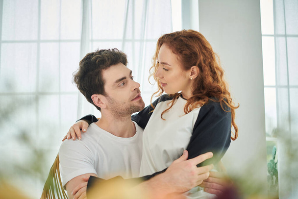 Un hombre tiernamente sostiene a una mujer en sus brazos mientras comparten un momento de intimidad y afecto. - Foto, imagen