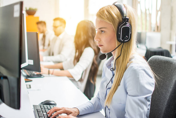 Blond businesswoman or helpline operator with headset using computer at office - Photo, Image
