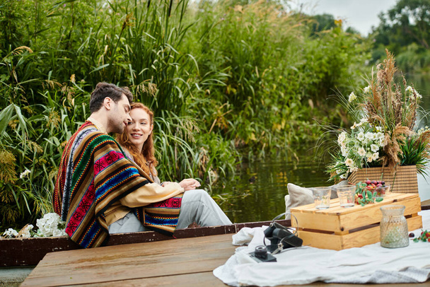 Un couple en tenue boho profitant d'une promenade romantique en bateau dans un cadre de parc verdoyant serein. - Photo, image