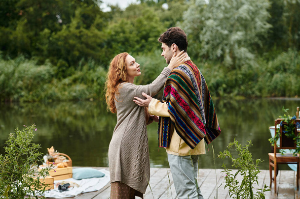 Чоловік і жінка, одягнені в одяг у стилі бохо, стоять поруч у пишному зеленому парку, створюючи романтичну сцену. - Фото, зображення