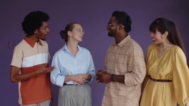 Retrato de grupo multiétnico de personas en ropa casual sonriendo a la cámara de pie sobre fondo púrpura - Metraje, vídeo